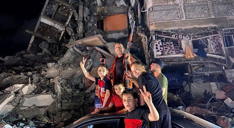 People gesture near the rubble of a damaged building as Palestinians celebrate in the streets following a ceasefire in Gaza City. Source: Reuters