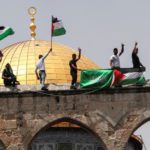 Palestinians hold flags as they stand at the compound that houses Al-Aqsa Mosque. Source: Reuters