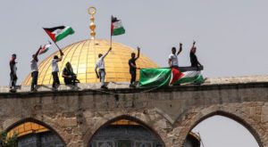 Palestinians hold flags as they stand at the compound that houses Al-Aqsa Mosque. Source: Reuters