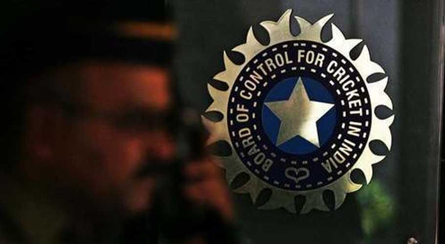 A policeman walks past a logo of the Board of Control for Cricket