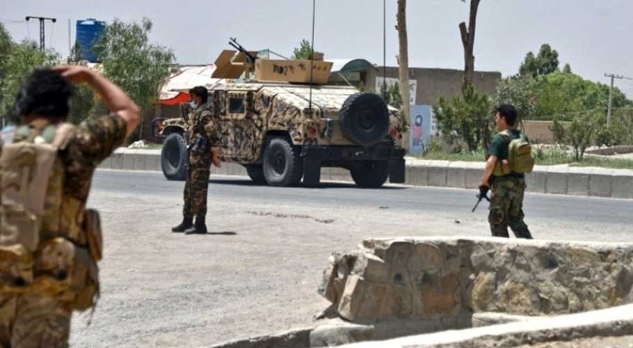 Afghan security personnel stand guard along the road amid fighting. (Source: AFP)