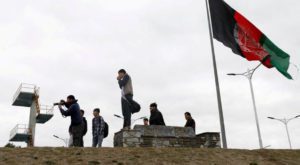 Youths take pictures next to an Afghan flag on a hilltop overlooking Kabul, Source: Reuters.