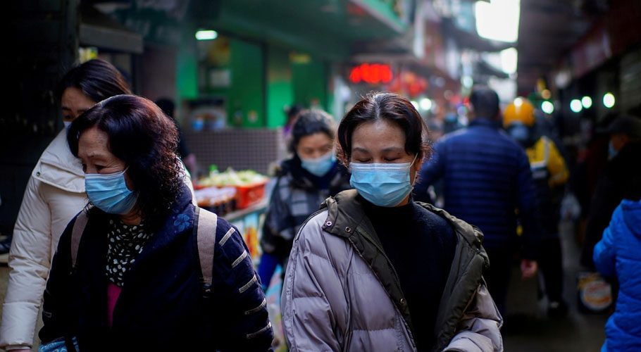 People wearing face masks walk on a street market following an outbreak of Covid-19 in Wuhan. Source: Reuters.