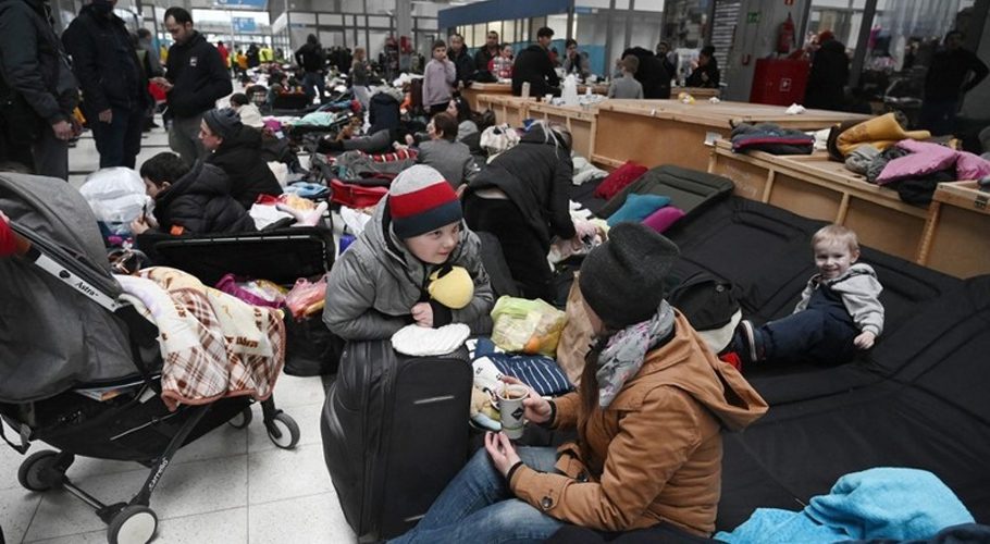 FILE PHOTO: People sit on camp beds in a refugee reception center at the Ukrainian-Polish border crossing in Korczowa, Poland, March 5, 2022 © AFP / Olivier Douliery
