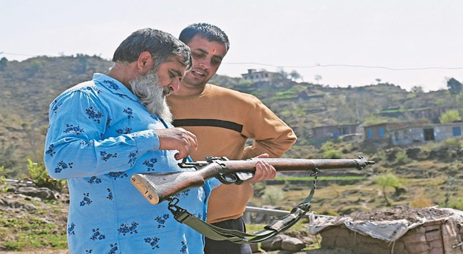 Abdul Qayoom, a retired Indian soldier, gives tips to civil servant Sanjeet Kumar (right) about using a bolt-action rifle in Dhangri village of India-held Kashmir.—AFP