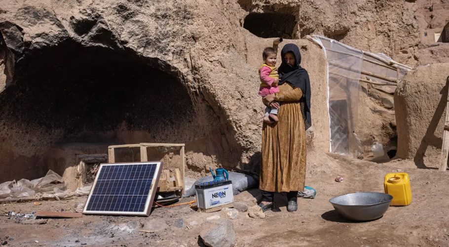 Fatima stands with her daughter in front of her home in a cave in Bamyan. She was displaced two years ago. When she moved back to Bamyan with three of her children, she had no money for rent and moved into a cave. [Julian Busch/UNHCR]