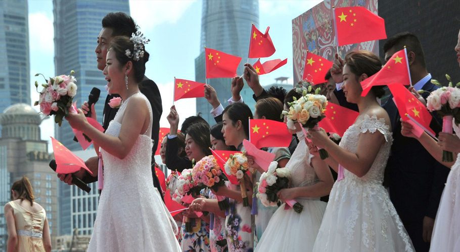 Couples wave Chinese flags as they attend a mass wedding in Shanghai.