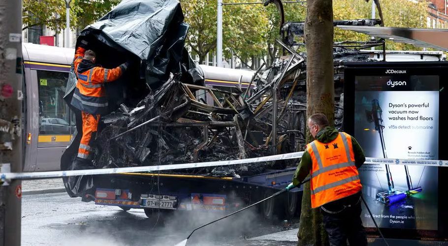 A worker covers up wreckage as another one cleans the street, following a riot in the aftermath of a school stabbing that left several children and adults injured, in Dublin, Ireland November 24, 2023. REUTERS/Clodagh Kilcoyne Acquire Licensing Rights