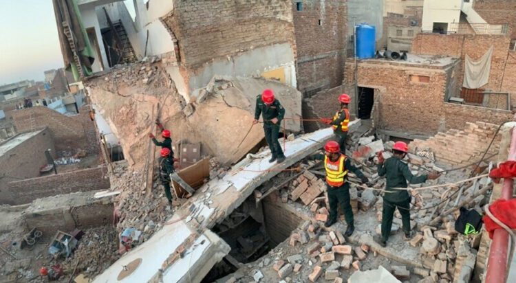 Rescue 1122 workers can be seen performing a rescue operation at the site of the collapsed building. — Photo Dawn.com