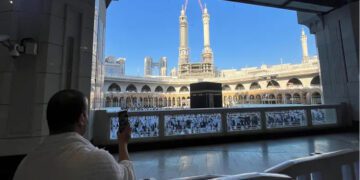 A Muslim man uses a mobile phone during Umrah, at the Grand Mosque, while construction cranes are seen in the background, in the holy city of Mecca, Saudi Arabia, December 18, 2023. (Reuters)