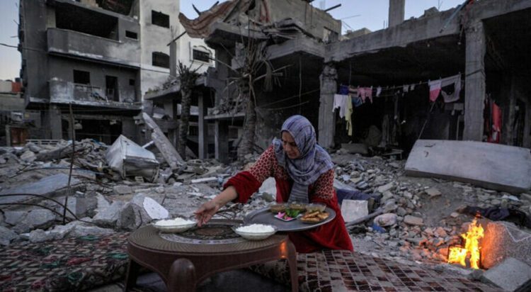 A Palestinian woman prepares a traditional Ramadan iftar meal amid the ruins of her family’s house. Photo: AFP