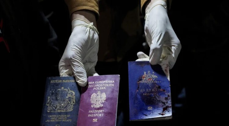 A man displays blood-stained British, Polish, and Australian passports after an Israeli airstrike, in Deir al-Balah, Gaza Strip, April 1, 2024. (AP Photo/Abdel Kareem Hana)