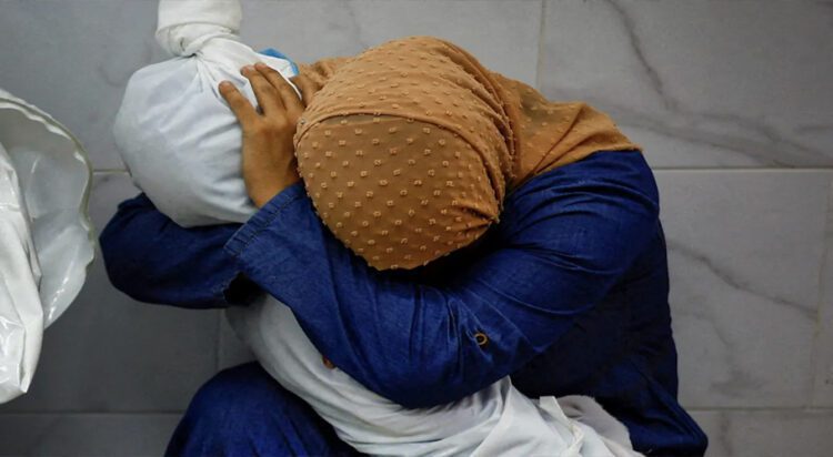 Inas Abu Maamar, 36, embraces the body of her five-year-old niece Saly, who was killed in an Israeli strike, at Nasser Hospital in Khan Younis in the southern Gaza Strip, on October 17, 2023. [Mohammed Salem/Reuters]
