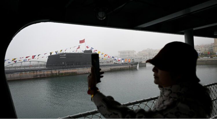 This picture taken during a media tour organised by the Chinese People's Liberation Army Navy (PLAN) to mark its 75th founding anniversary, shows a woman taking pictures of a submarine at the PLA Naval Museum in Qingdao, China's Shandong province on April 23, 2024. (AFP/File)