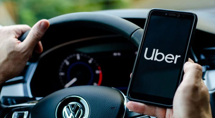 FILE An Uber driver holding a smartphone in a Volkswagen car, 2019.
Lutsenko_Oleksandr/Shutterstock.com