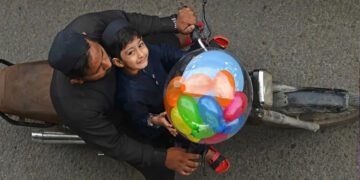 A boy carries a balloon on a motorbike after offering Eid al-Fitr prayers, marking the end of the holy fasting month of Ramadan, in Karachi on April 10, 2024. (AFP)