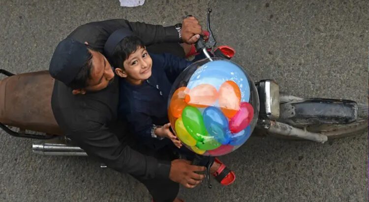 A boy carries a balloon on a motorbike after offering Eid al-Fitr prayers, marking the end of the holy fasting month of Ramadan, in Karachi on April 10, 2024. (AFP)