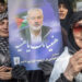 An Iranian woman holding a poster of Hamas leader Ismail Haniyeh during a symbolic funeral procession in Tehran, (August 2024) (Getty Images)