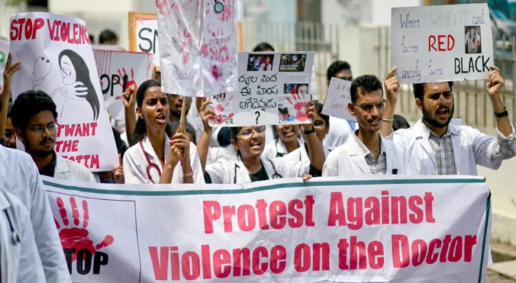 Doctors hold posters to protest the rape and murder of a young medic from Kolkata, at the Government General Hospital in Vijayawada on August 14 [Idrees Mohammed/AFP]