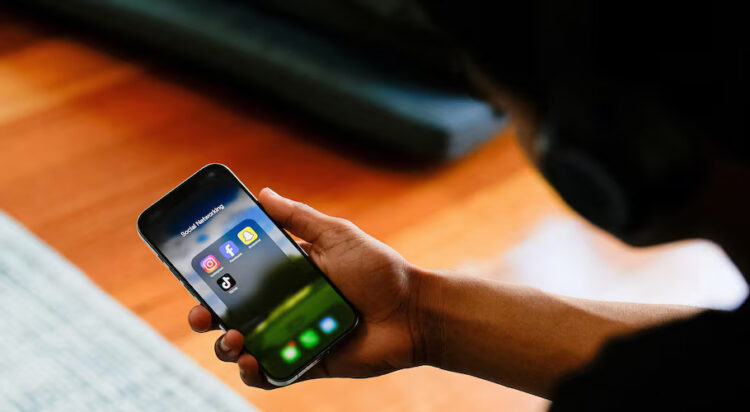 A high school student poses with his mobile phone showing his social media applications in Melbourne, Australia, November 28, 2024. REUTERS/Asanka Brendon Ratnayake