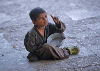 In this file photo, a boy gestures as he begs while sitting along a sidewalk in Karachi Oct. 17, 2012. (AP)