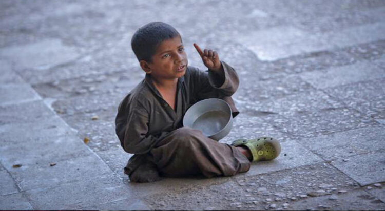 In this file photo, a boy gestures as he begs while sitting along a sidewalk in Karachi Oct. 17, 2012. (AP)