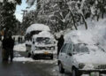 A man tries to clear snow off a vehicle on a road in Murree. — AFP/File