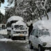 A man tries to clear snow off a vehicle on a road in Murree. — AFP/File