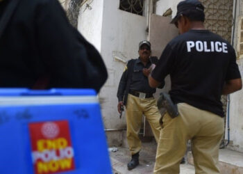 Policemen escort a polio vaccination team during a door-to-door campaign in June (Getty Images)