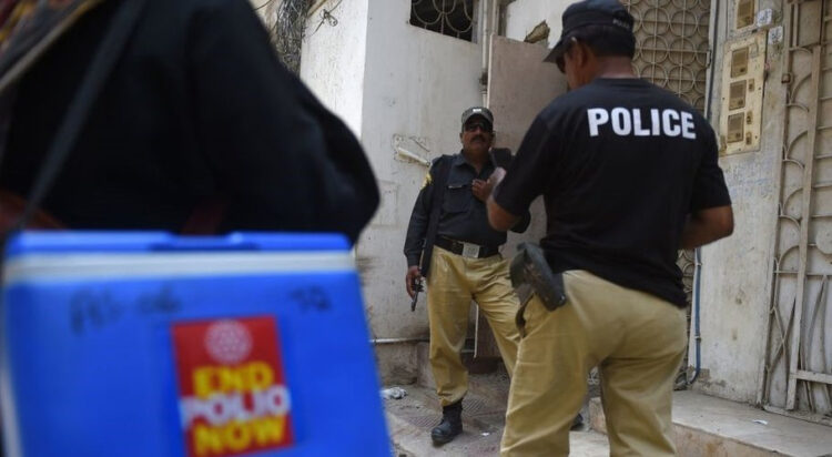 Policemen escort a polio vaccination team during a door-to-door campaign in June (Getty Images)