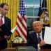 President Donald Trump holds up an executive order commuting sentences for people convicted of January 6 offences, in the Oval Office of the White House, Monday, January 20, 2025, in Washington, DC [Evan Vucci/AP]