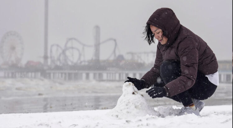 Paige Encarnacion builds a snowman on the beach during a winter storm on Tuesday, Jan. 21, 2025 in Galveston, Texas. (Brett Coomer/Houston Chronicle via AP)