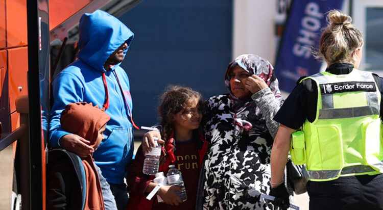 A migrant pregnant woman is helped to board on a bus in order to be taken for processing on the southeast coast of England. (File/AFP)