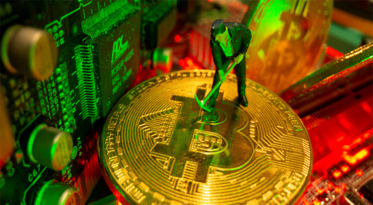 A small toy figure and representations of the virtual currency bitcoin stand on a motherboard in this picture illustration taken May 20, 2021. REUTERS/Dado Ruvic/Illustration/File Photo
