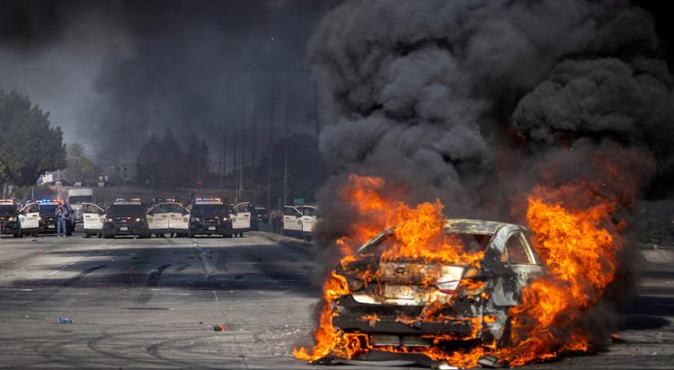 A car burns on Atlantic Boulevard during a standoff by protesters and law enforcement, following multiple detentions by Immigration and Customs Enforcement (ICE), in the Los Angeles County city of Paramount, California, U.S., June 7, 2025. REUTERS/Barbara Davidson