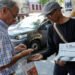 Ali Akbar, 73, known as the last newspaper hawker in the French capital sells 'Le Monde' newspaper to a man on the street in the Latin Quarter, in Paris, France, August 4, 2025. (REUTERS)