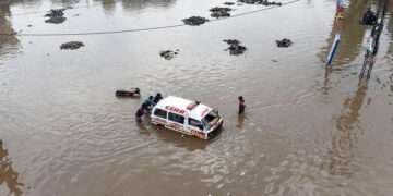 Men push an ambulance through a flooded square. —AFP