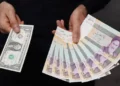 A currency dealer poses for a photo with a U.S one dollar bill and the amount being given when converting it into Iranian rials in an exchange shop in Tehran, Iran December 25, 2022. Majid Asgaripour/WANA (West Asia News Agency) via REUTERS