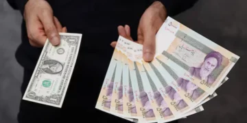 A currency dealer poses for a photo with a U.S one dollar bill and the amount being given when converting it into Iranian rials in an exchange shop in Tehran, Iran December 25, 2022. Majid Asgaripour/WANA (West Asia News Agency) via REUTERS